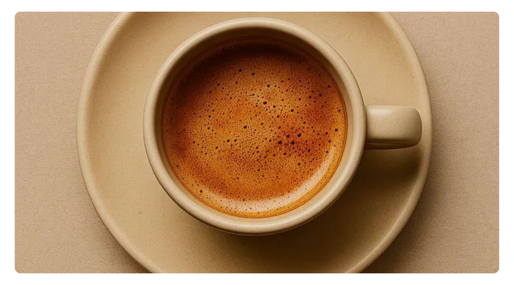 “Cup of hot coffee with rich crema served in a beige ceramic cup and saucer on a neutral background.”